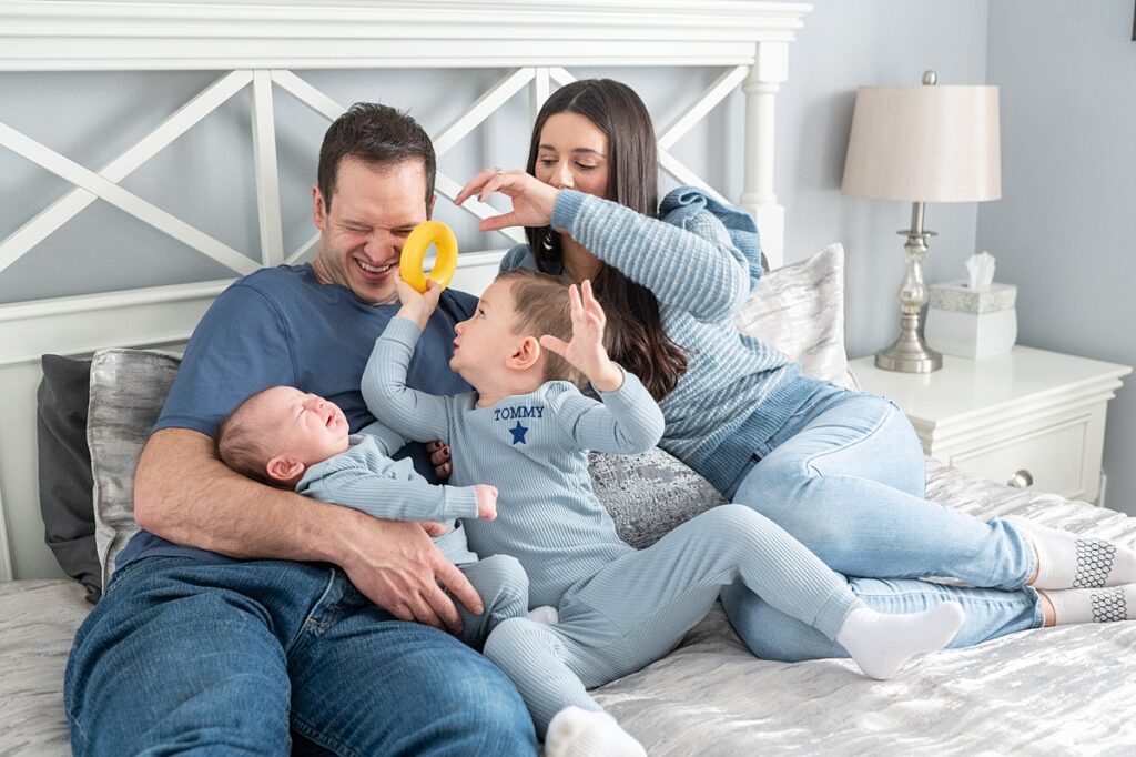 Family dressed in blue tones for a photography session at home on their bed.