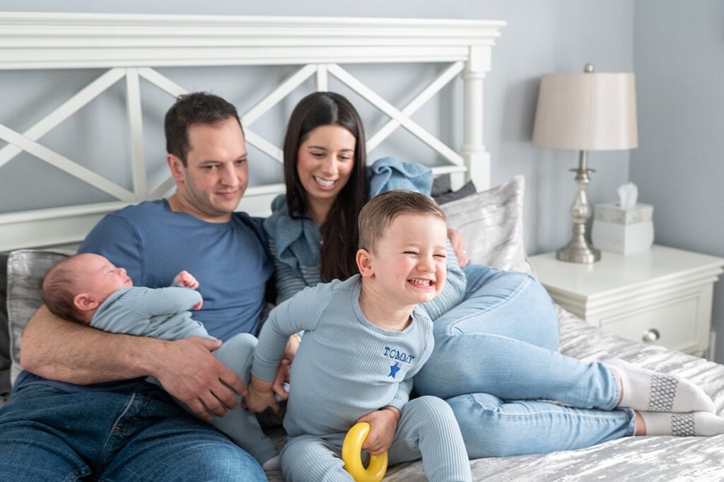 Family dressed in blue tones for a photography session at home on their bed.