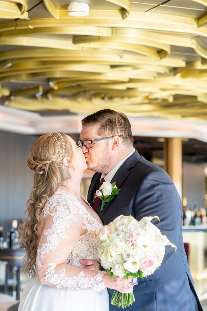 Bride and groom kiss in The Rose bar on Wish, with Disney Cruise Line.