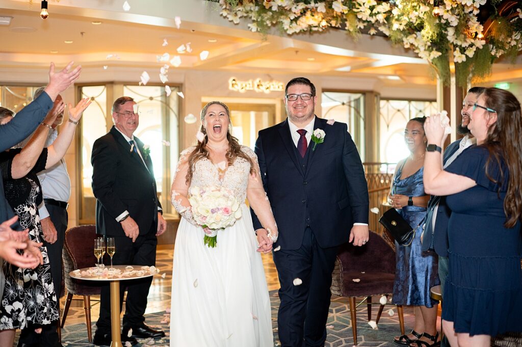 Bride and groom walking through a petal toss after their wedding ceremony at The Bayou on Disney Wish.