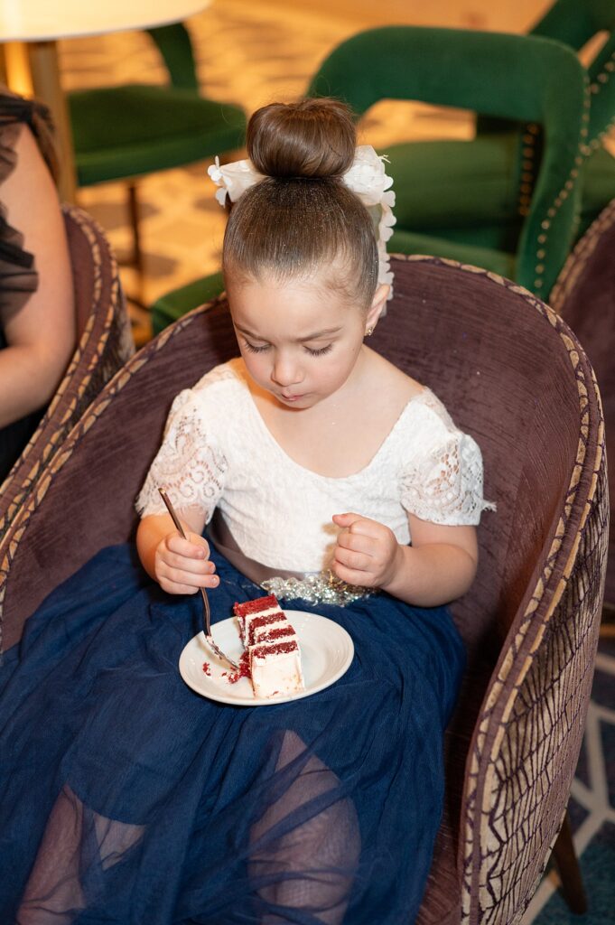 Flower girl eating a slice of red velvet cake during a Disney Cruise wedding at The Bayou.