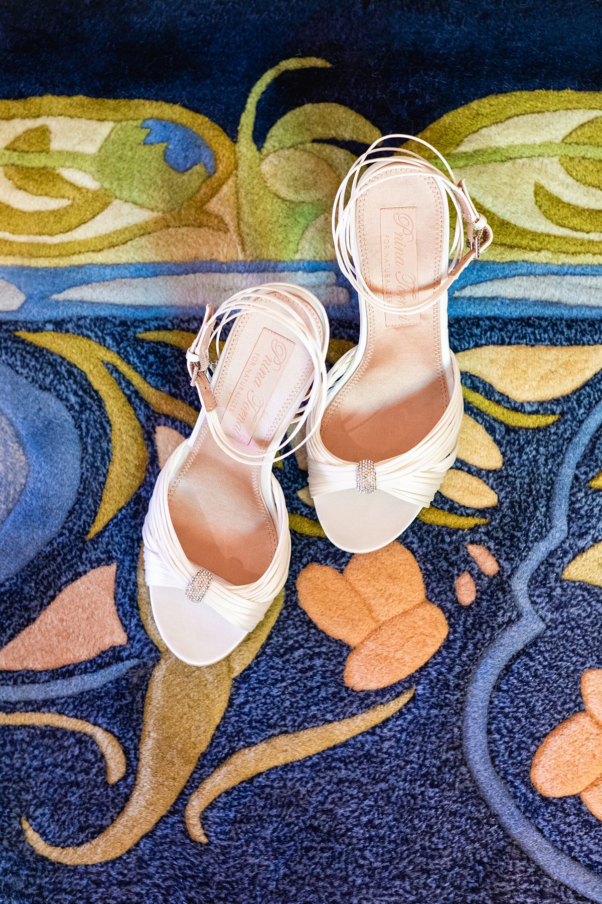 White wedding shoes for the bride during her Disney Cruise Line wedding with a colorful backdrop on Fantasy.