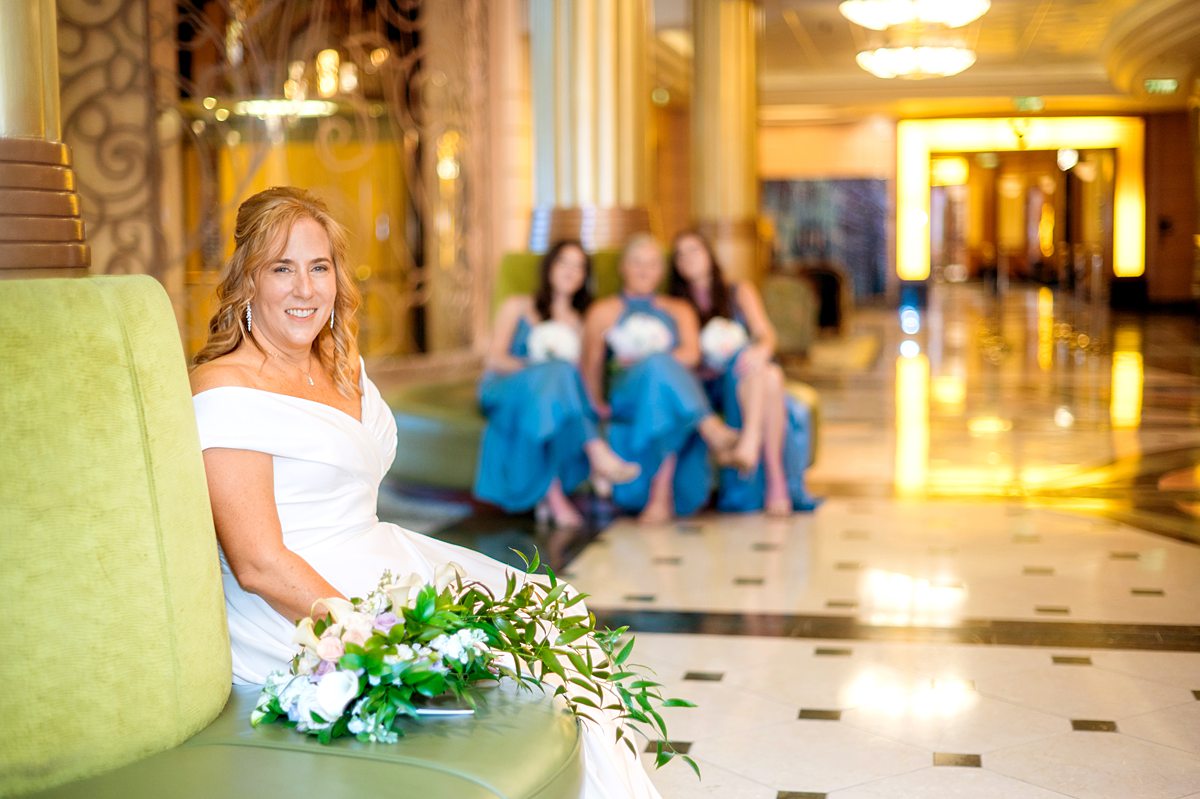 Bride on Disney Cruise Line Fantasy ship for her wedding with the bridesmaids in blue in the background.