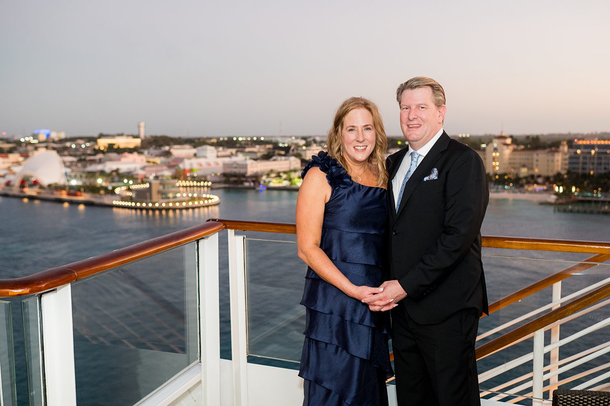 A woman and a man in formal wear with a sunset sky on Disney Fantasy.