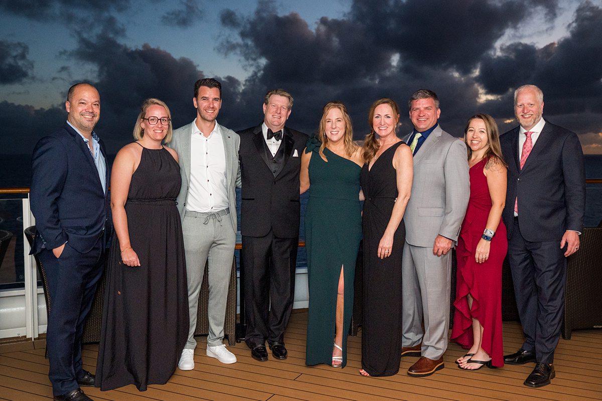 Group of men and women in formal attire with a dusk sky on Disney Fantasy.