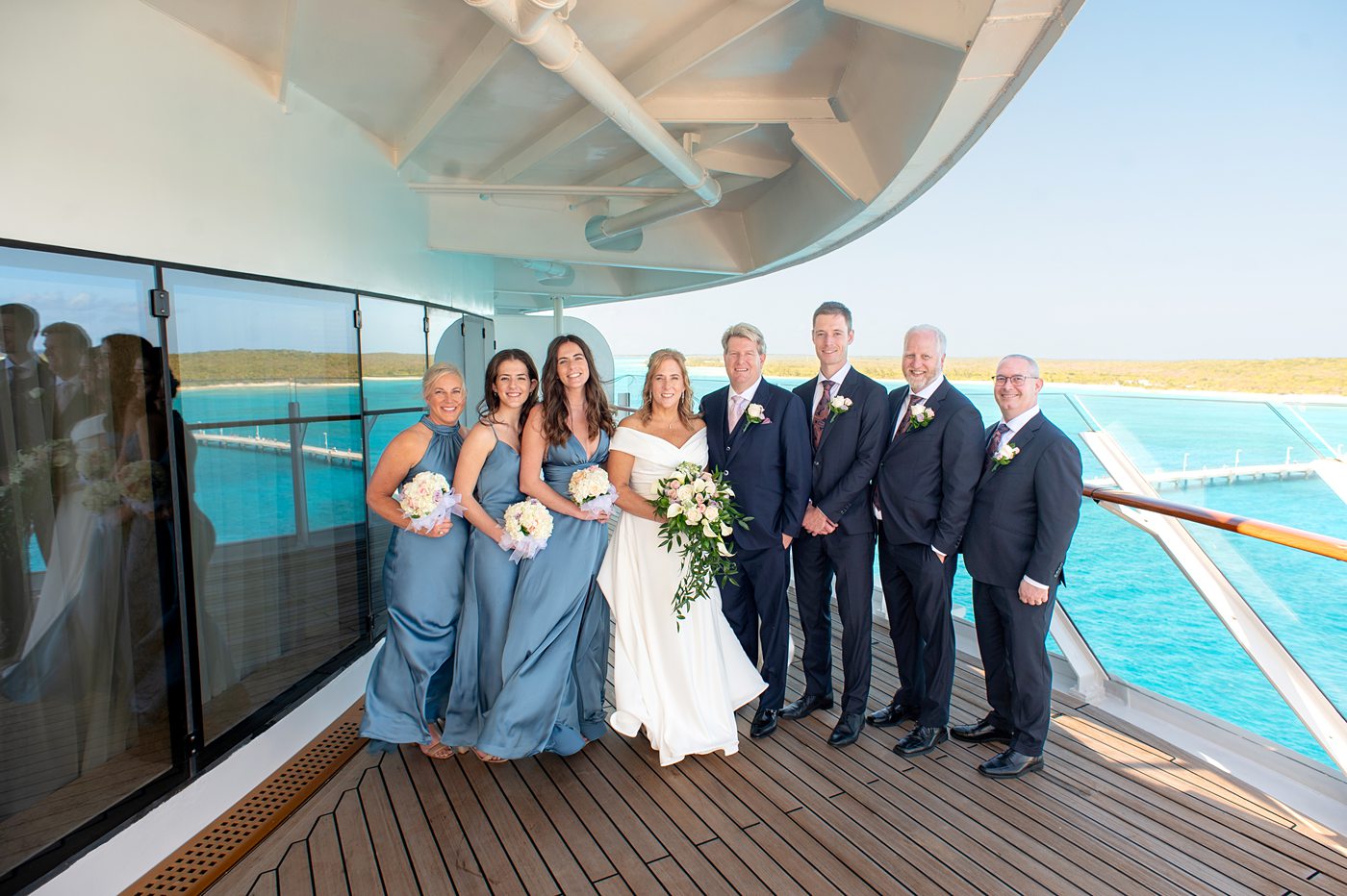 Wedding party/bridal party on balcony of the Walt Disney Suite with the Caribbean sea in the background, during a Disney Cruise Line wedding on Fantasy. 